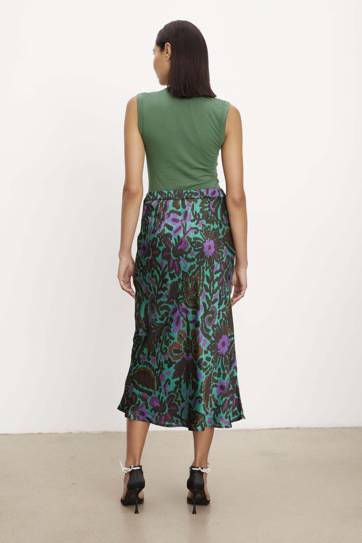   The back view of a woman wearing a KAIYA PRINTED SKIRT by Velvet by Graham & Spencer satin viscose midi skirt. 