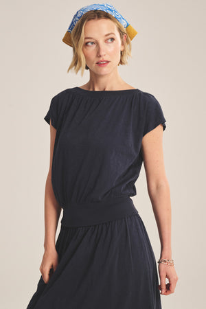 Woman wearing the Velvet by Graham & Spencer AUDEN TEE in navy, styled with a blue patterned headscarf, gazing slightly to the side against a plain background.