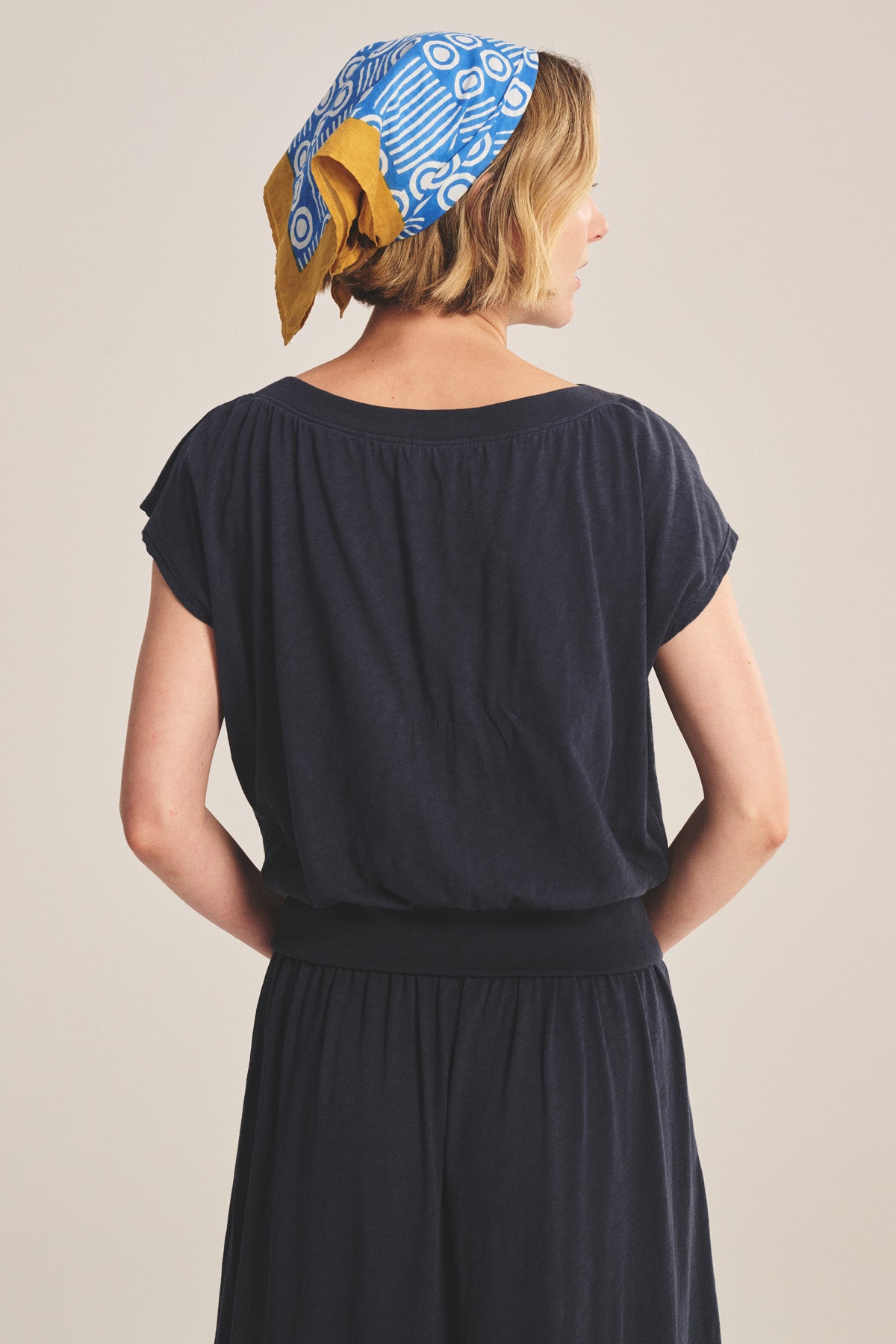 A person with short blond hair wears the AUDEN TEE by Velvet by Graham & Spencer, styled for everyday wear in navy, shown from the back.-41296654827713