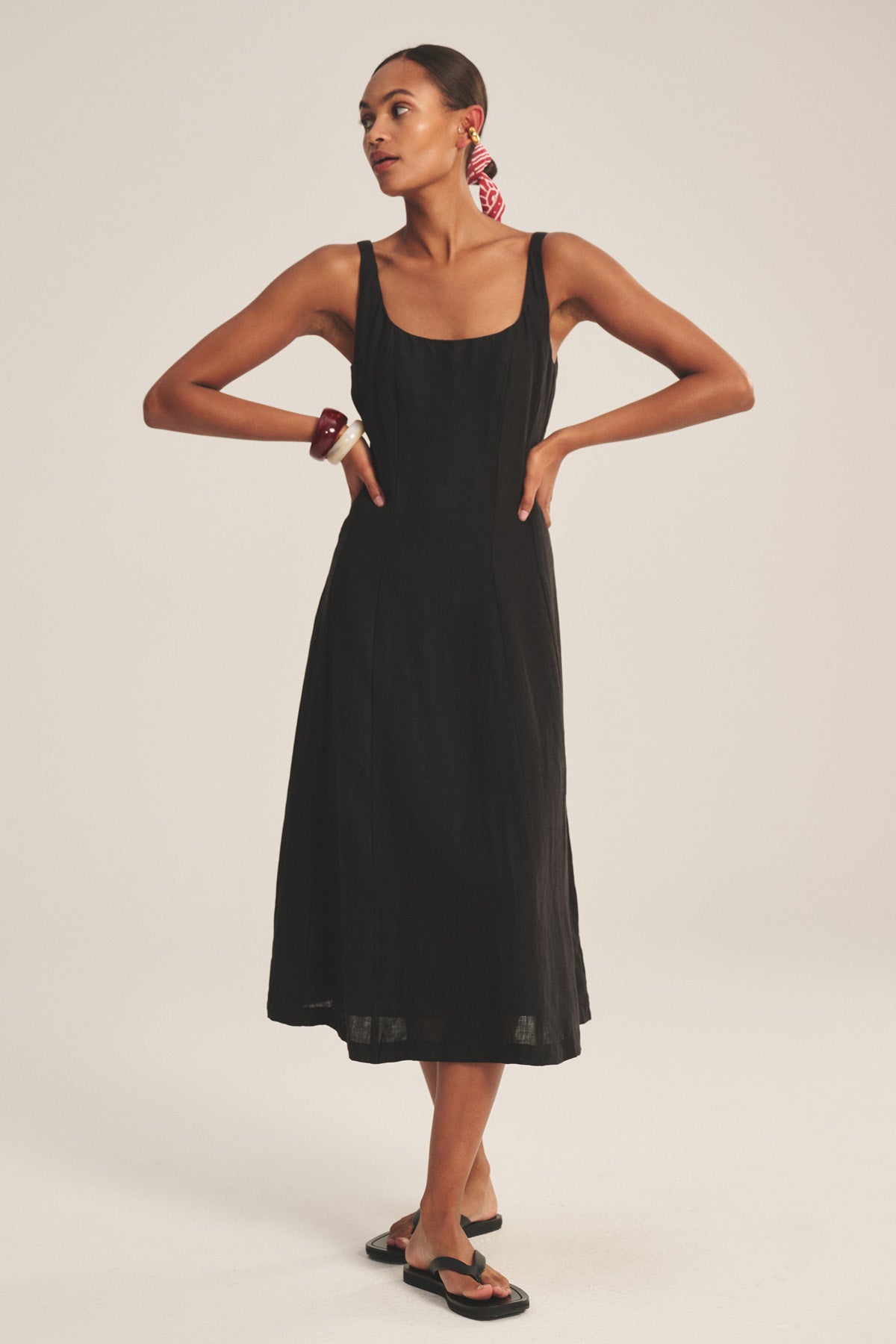 A woman wears the AUSTEN LINEN DRESS by Velvet by Graham & Spencer with black sandals, a red hair scarf, and a bracelet, set against a plain light background.-41080160977089