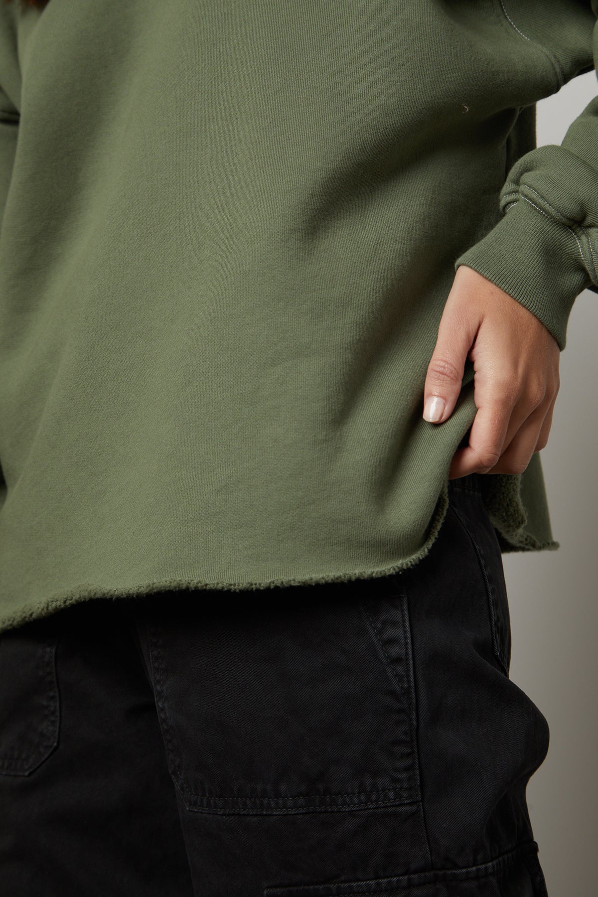   A woman wearing a green Velvet by Graham & Spencer DAX oversized fit sweatshirt and black pants. 