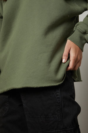 A woman wearing a green Velvet by Graham & Spencer DAX oversized fit sweatshirt and black pants.