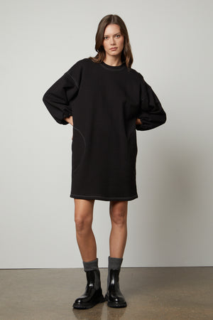 A model wearing a Velvet by Graham & Spencer JENSEN PUFF SLEEVE DRESS and black boots.