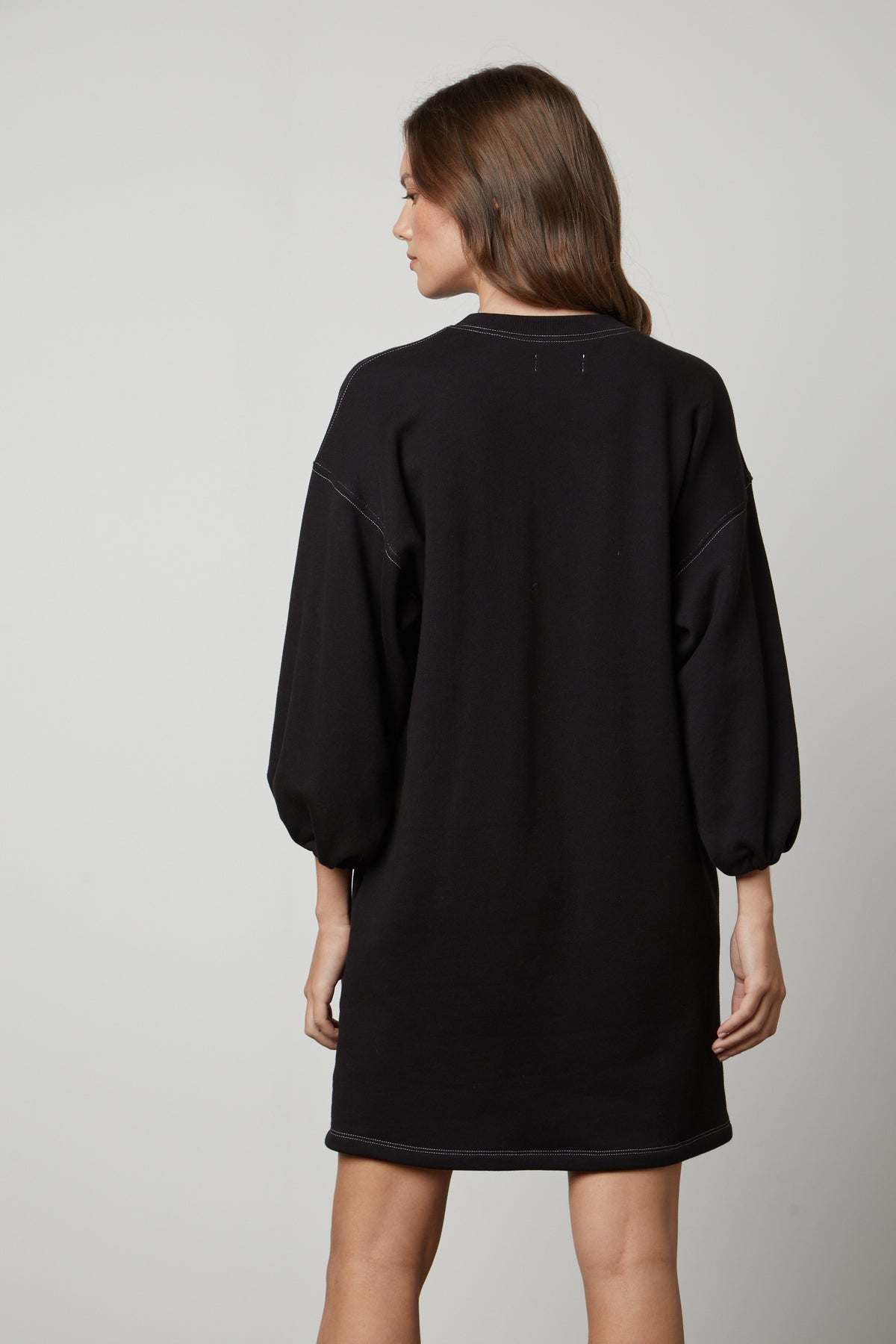 The back view of a woman wearing a Velvet by Graham & Spencer JENSEN PUFF SLEEVE DRESS.-26883616899265