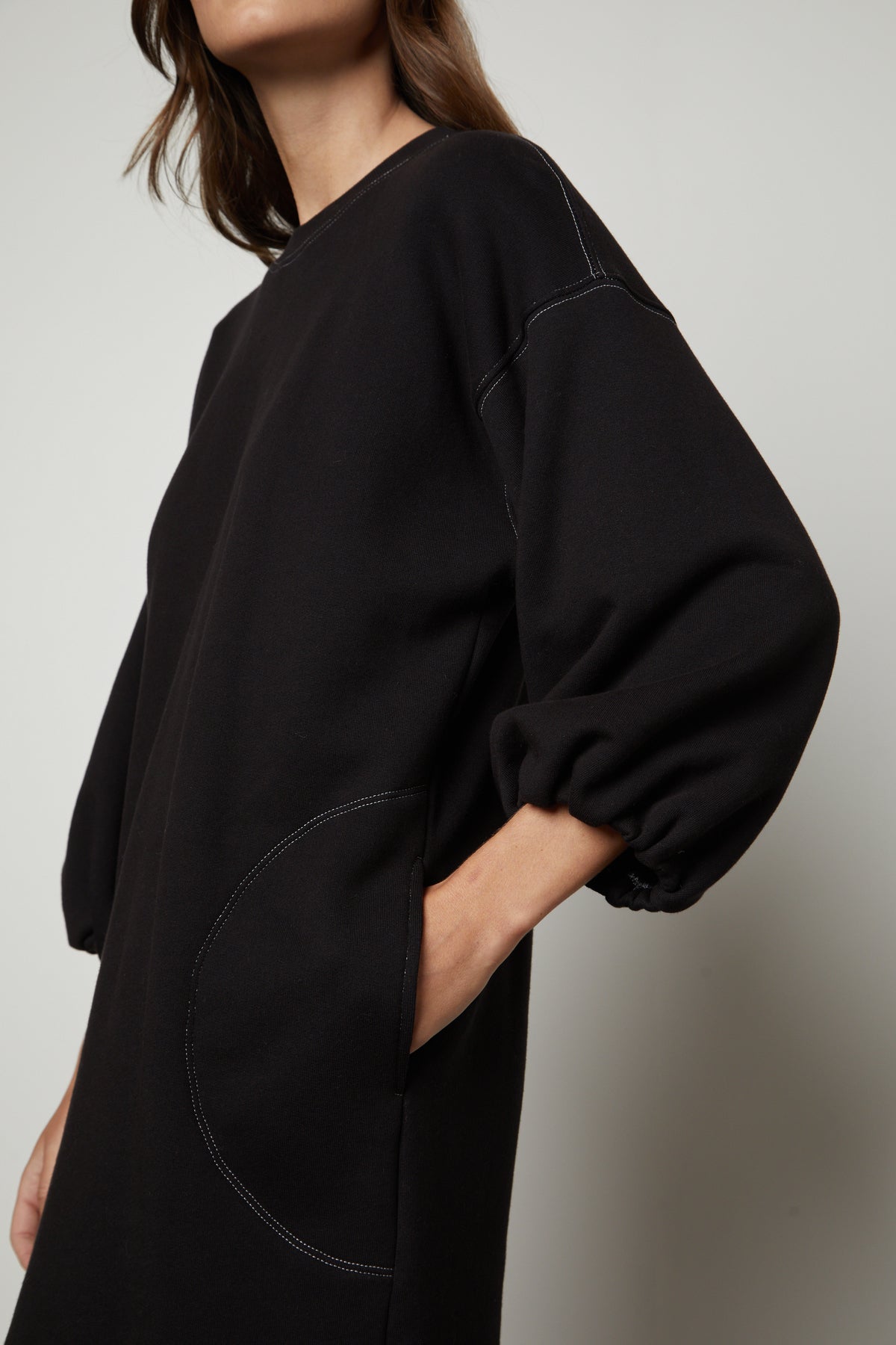   The model is wearing a Velvet by Graham & Spencer black sleeveless dress with pockets. 