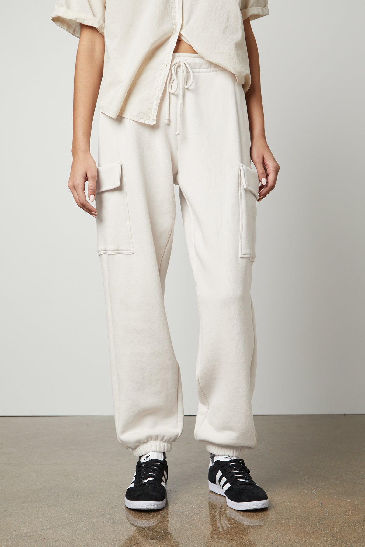 The model is wearing Velvet by Graham & Spencer's LUMI DRAWSTRING WAIST SWEATPANT and white sneakers.-26799843344577