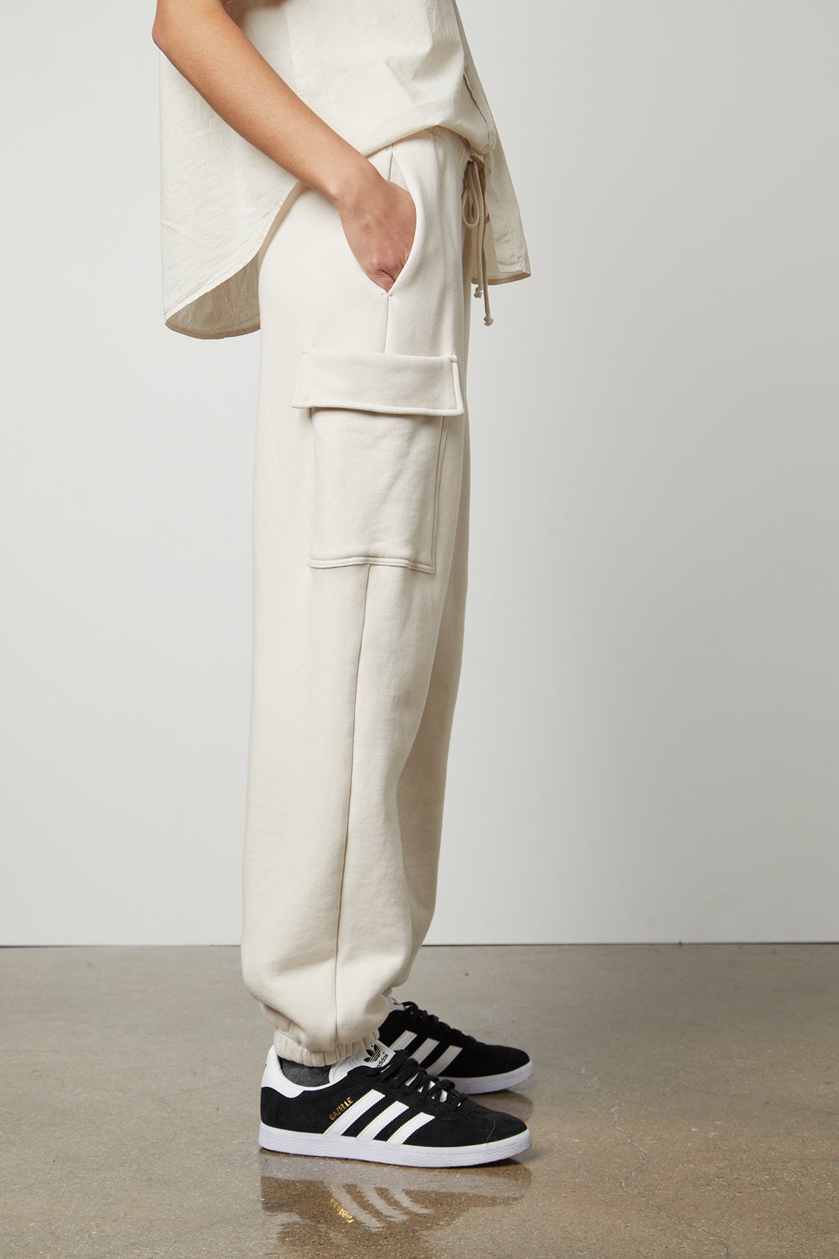   The model is wearing a white LUMI DRAWSTRING WAIST SWEATPANT and black sneakers. 