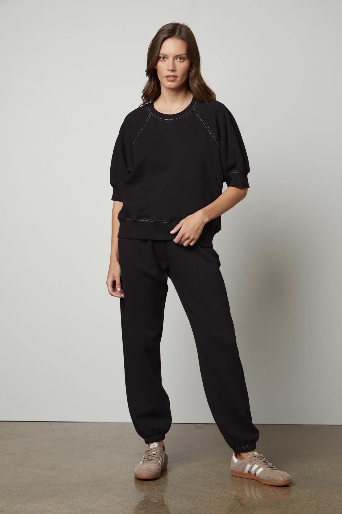 The model is wearing a black sweatshirt for warmth and Velvet by Graham & Spencer joggers for comfort.-35678661214401