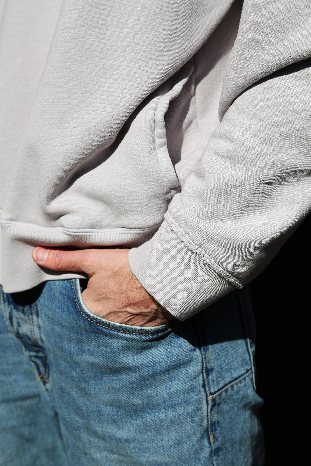   A person wearing a FORREST SWEATSHIRT by Velvet by Graham & Spencer in light gray, paired with blue jeans and with one hand in the pocket. 