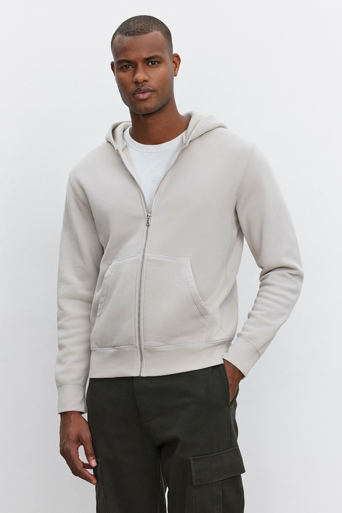 A man wearing the Velvet by Graham & Spencer REN HOODIE in light grey and dark green vintage-style pants stands against a plain white background.-37893921145025