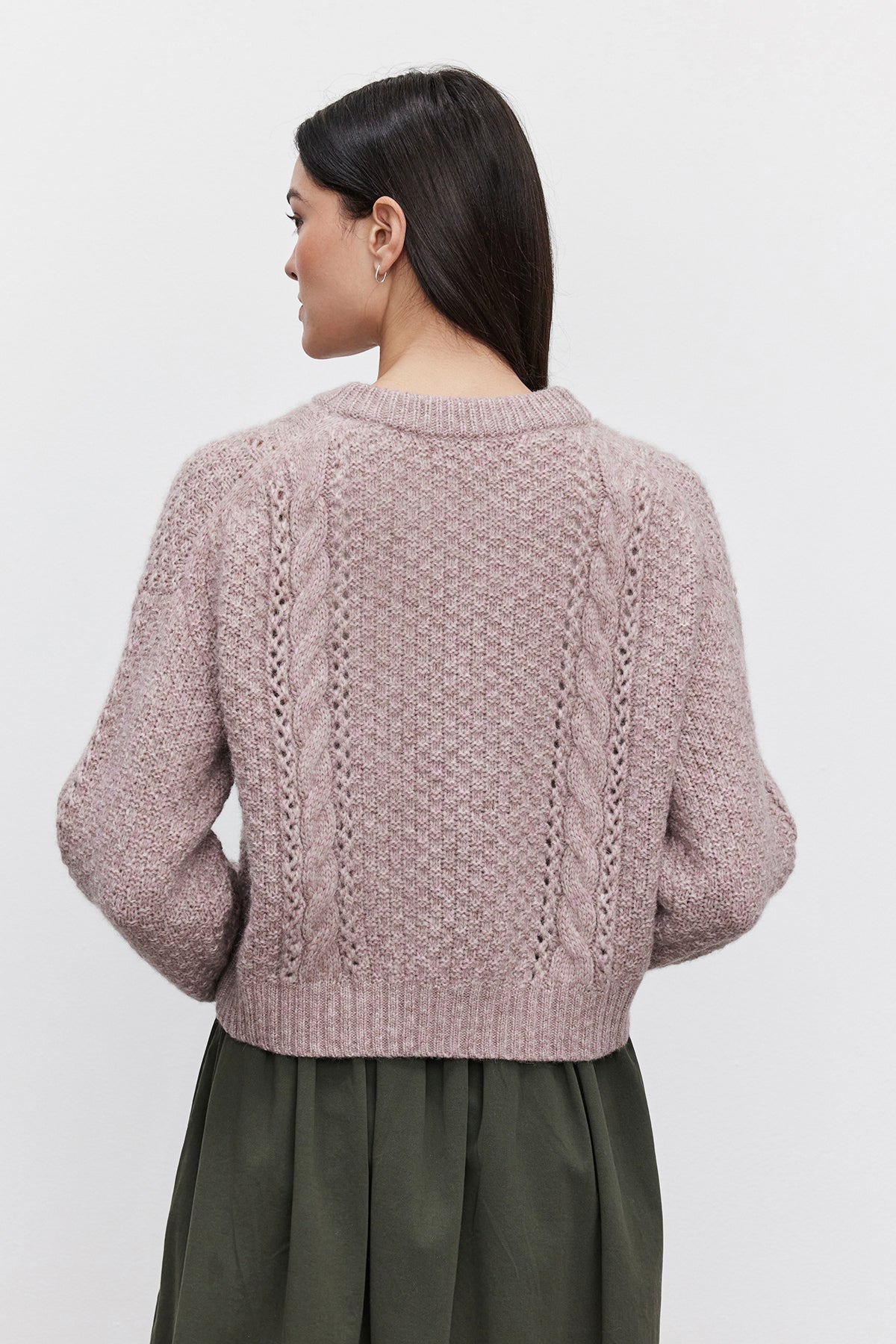   A person with long dark hair is shown from the back, wearing a light purple MARLEY SWEATER by Velvet by Graham & Spencer and a green skirt, standing against a plain white background. 