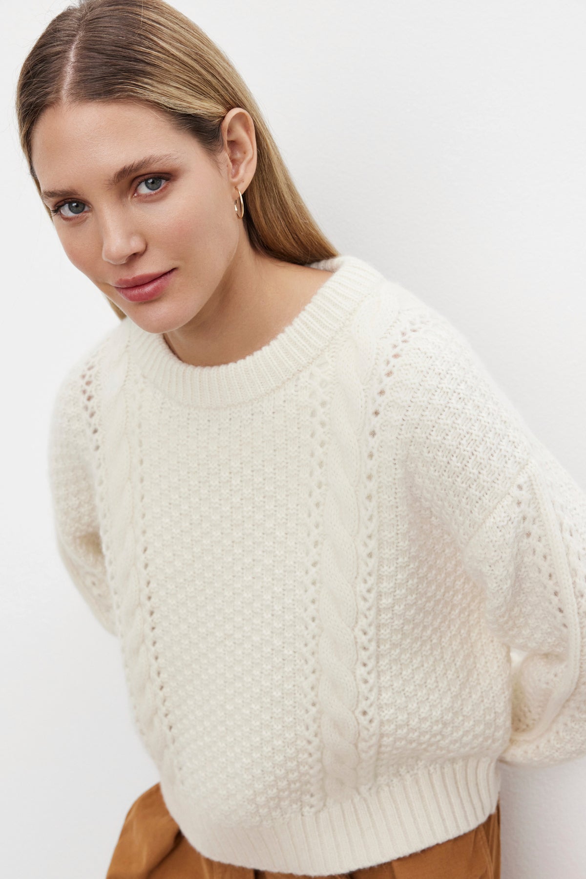 A person with long, blonde hair wearing the MARLEY SWEATER by Velvet by Graham & Spencer, which features a cream-colored, alpaca blend material and a textured knit design, is looking at the camera with a neutral expression against a plain white background.-37856341098689