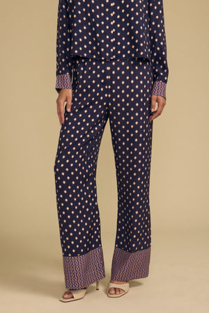 Velvet by Graham & Spencer CAROL PRINTED PANT: wide-leg navy blue viscose trousers with a repeating light pink diamond pattern and a contrasting geometric border at the hem, suitable for special occasions.