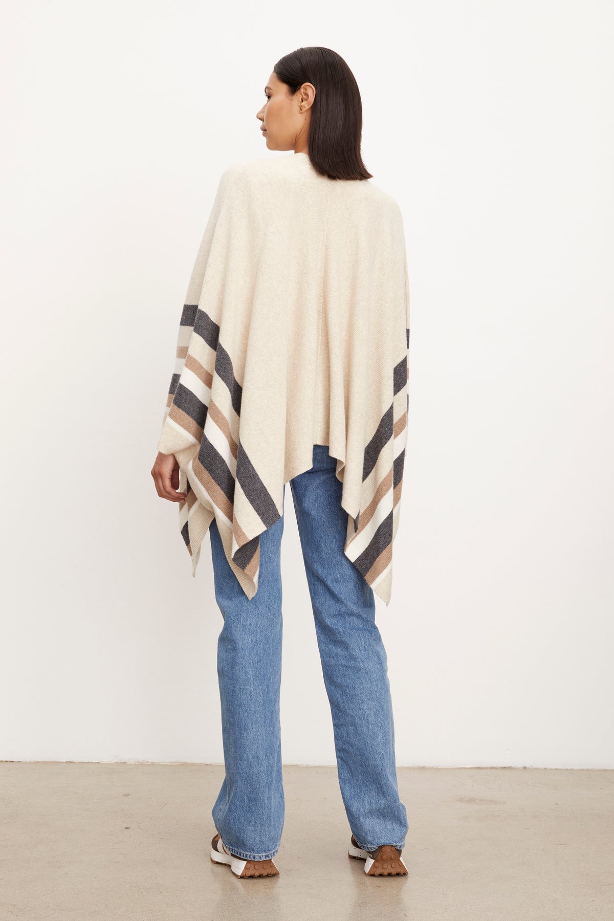 The back view of a woman wearing jeans and a Velvet by Graham & Spencer HARPER OPEN FRONT PONCHO.-26897793024193
