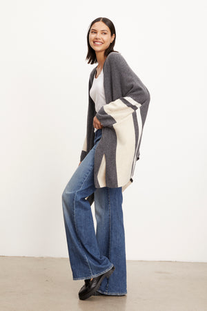 A model wearing the Velvet by Graham & Spencer HARPER OPEN FRONT PONCHO and flared jeans.