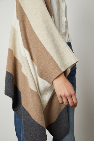 A woman wearing a Velvet by Graham & Spencer JONAS STRIPED OPEN FRONT PONCHO with striped detailing.
