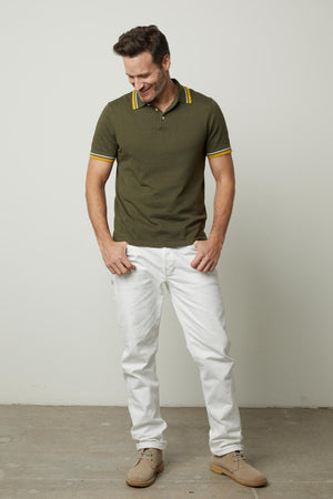 A man wearing the Velvet by Graham & Spencer GREGAN LINEN BLEND POLO and white pants.