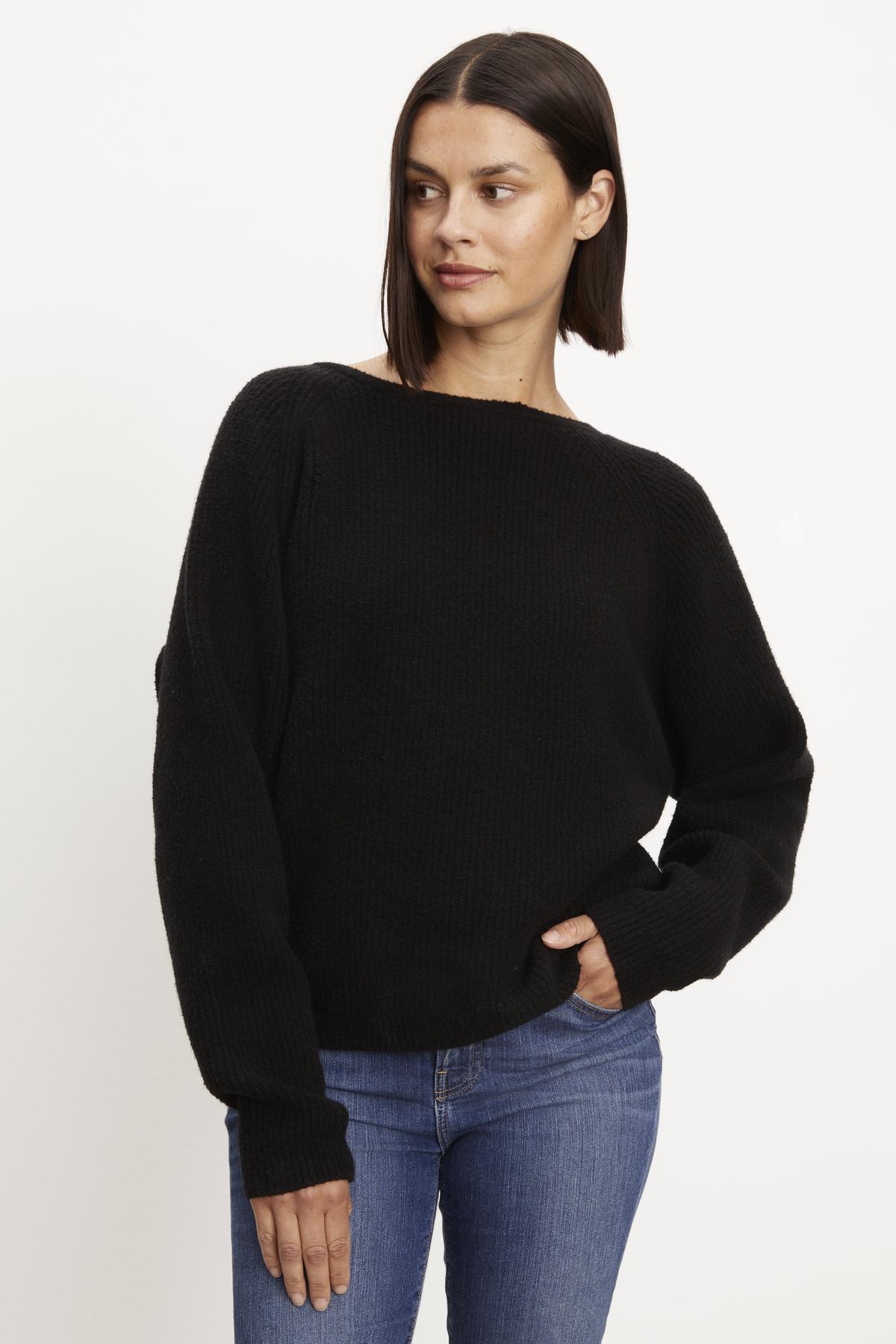   A model wearing a black Velvet by Graham & Spencer Caitlyn Boucle Raglan Sweater and jeans. 