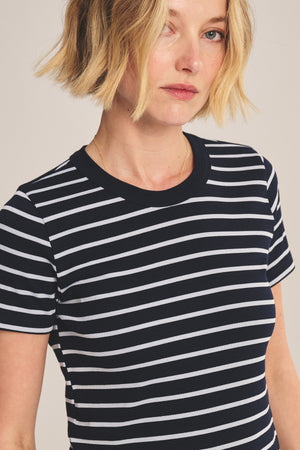 A person with short blonde hair models the BRENDA TEE by Velvet by Graham & Spencer—a black and white striped, cropped tee with a ribbed crew neckline—against a plain background.