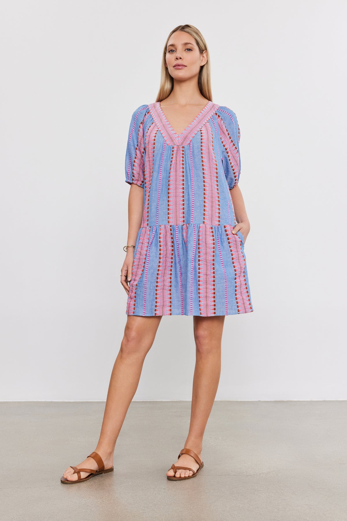   A woman in a ZOELLE DRESS by Velvet by Graham & Spencer with a v-neckline and sandals stands against a plain white background. 