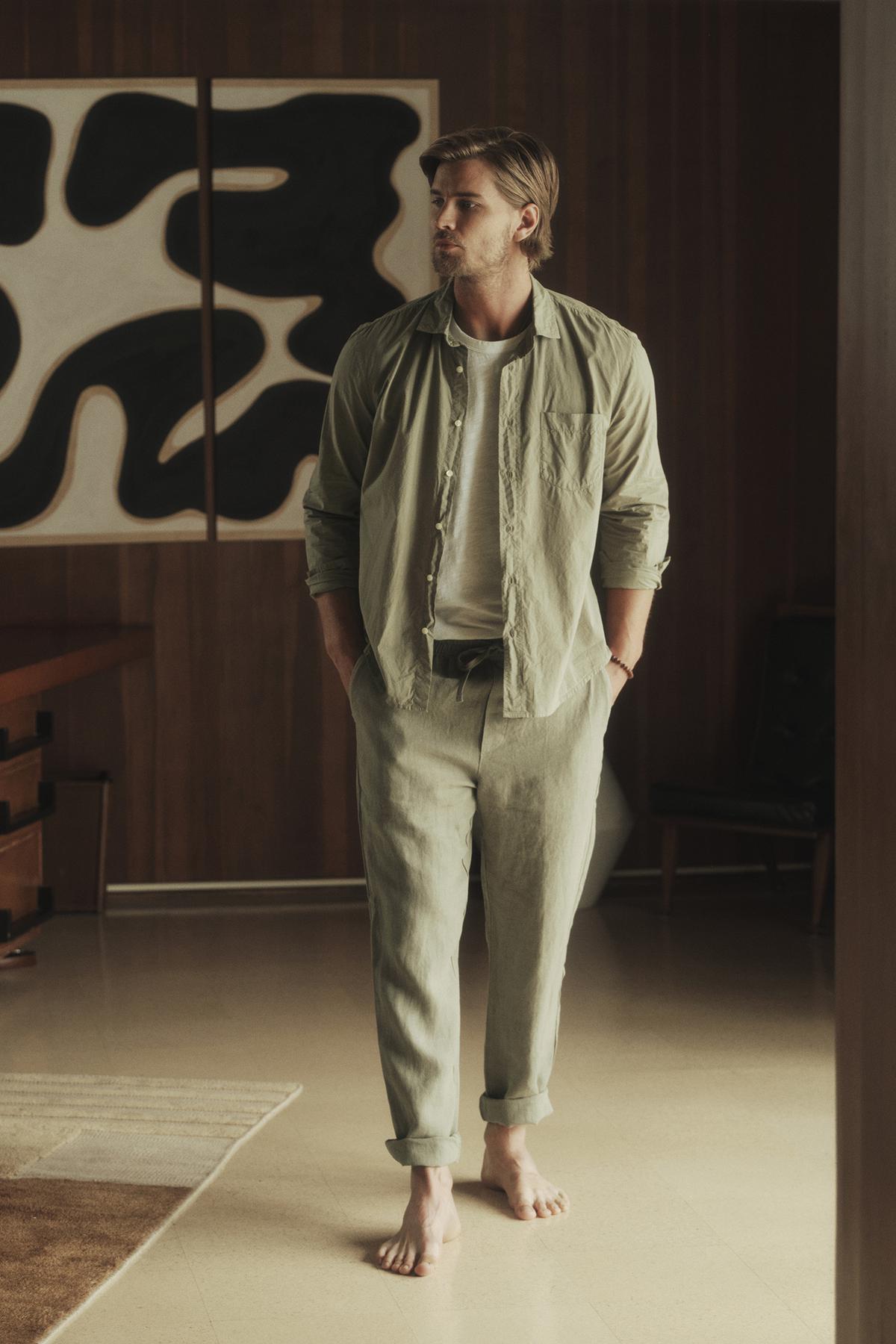   A man standing in a room wearing a Velvet by Graham & Spencer BROOKS BUTTON-UP SHIRT and pants. 
