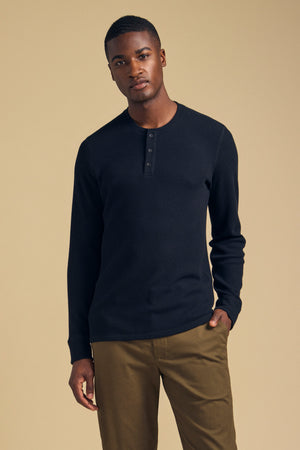 A man wearing a black Velvet by Graham & Spencer ROEN THERMAL HENLEY, a long-sleeved brushed shirt with a buttoned placket.