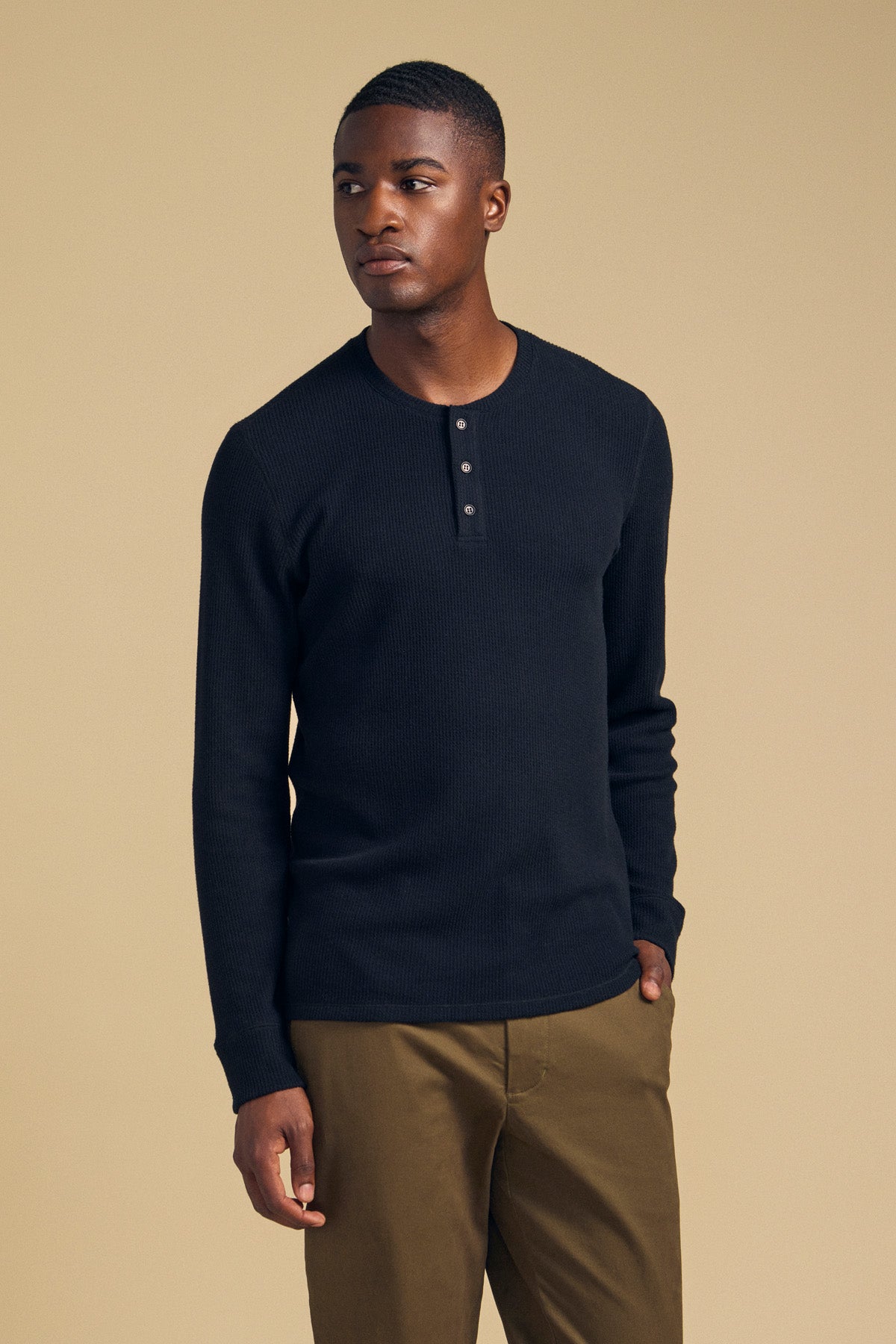 A man wearing a black ROEN THERMAL HENLEY, a long-sleeved shirt with a three-button placket perfect for cold-weather wear.