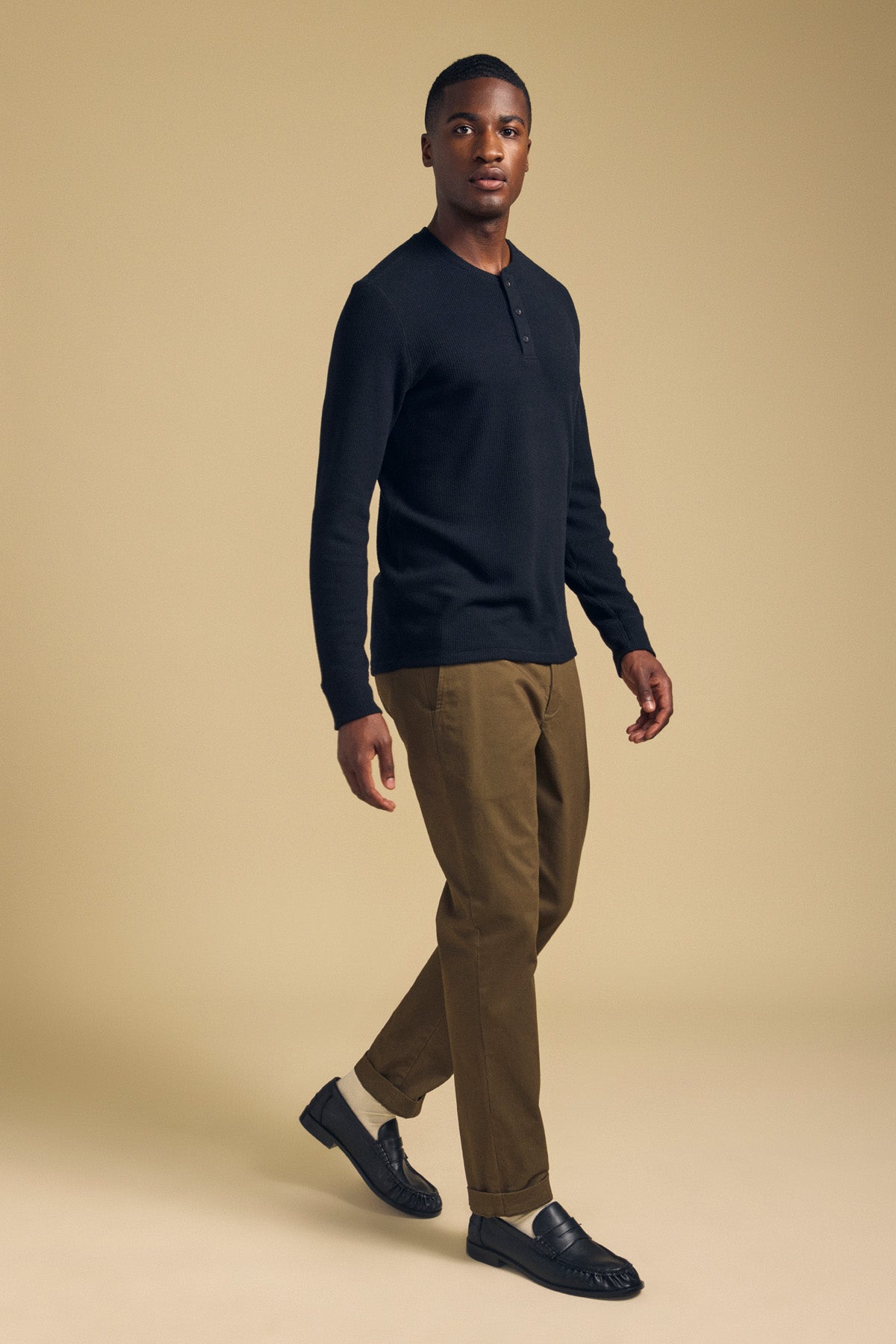 A man wearing a black ROEN THERMAL HENLEY, olive trousers, and black loafers.-46288291135681