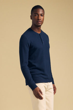 A man wearing a navy blue ROEN THERMAL HENLEY by Velvet by Graham & Spencer, a brushed thermal shirt with a three-button placket.