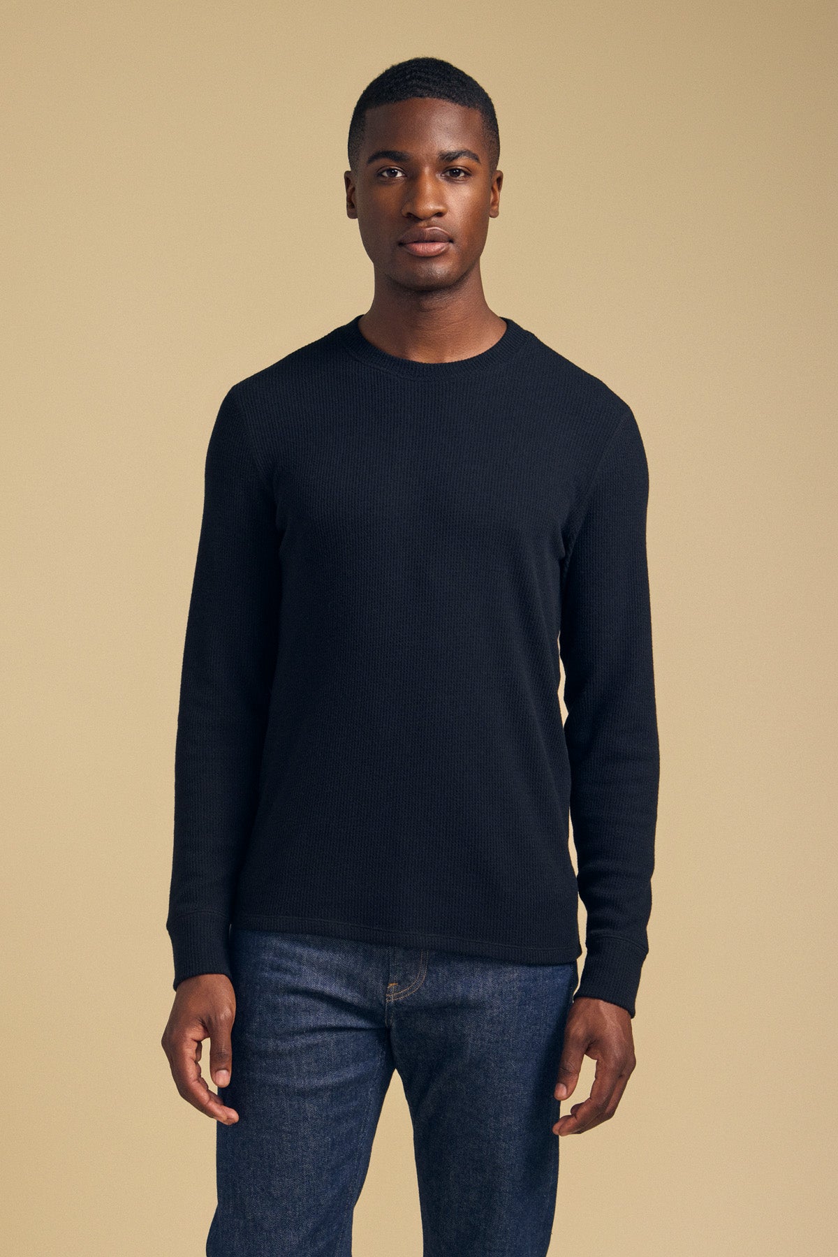 A man wearing a black brushed TOLLIVER THERMAL CREW PULLOVER and blue jeans.