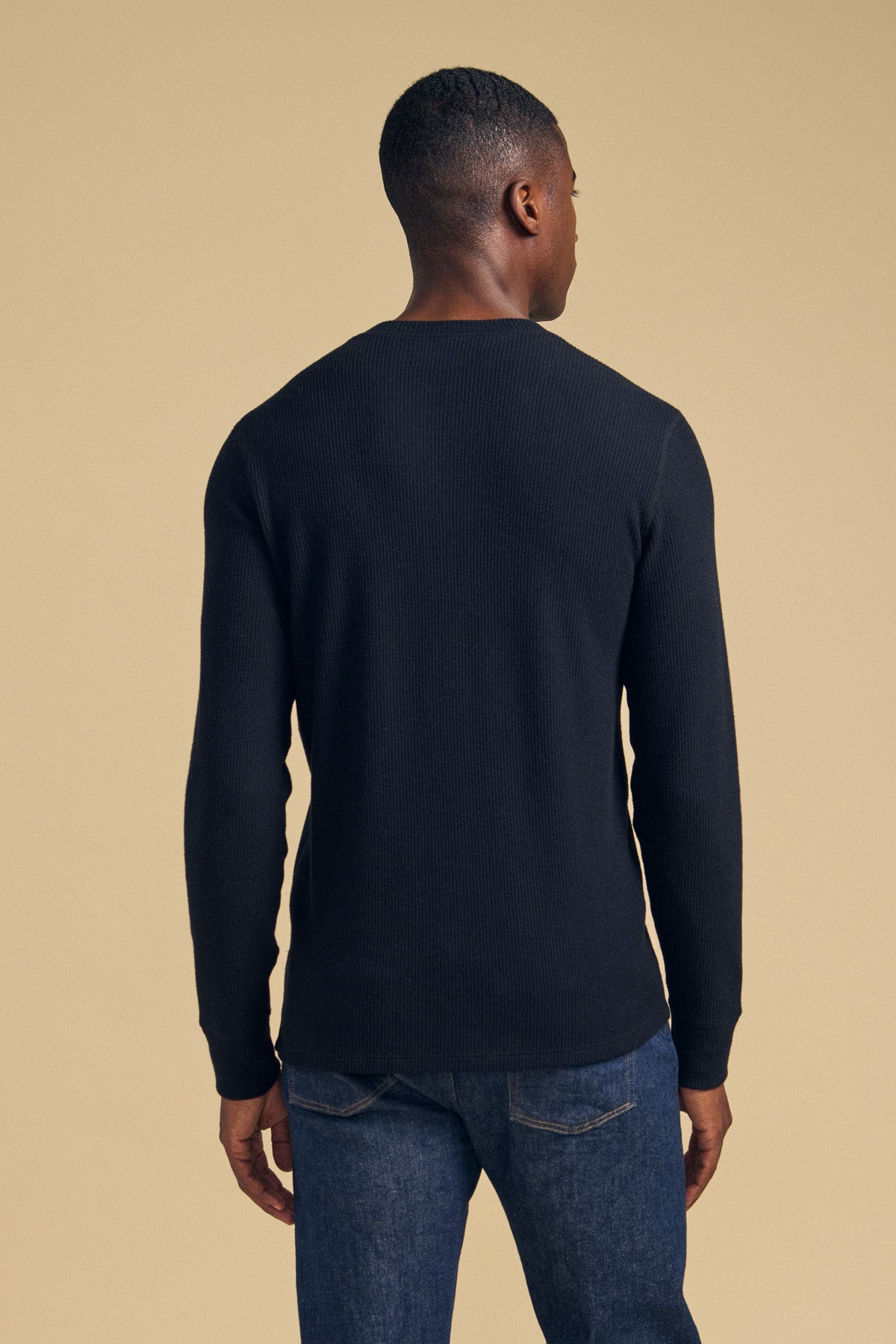 Back view of a person wearing a black long-sleeved Velvet by Graham & Spencer TOLLIVER THERMAL CREW PULLOVER and blue jeans.