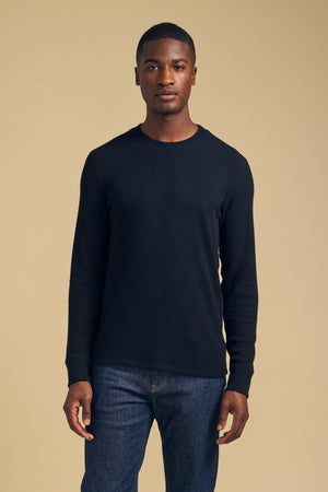 A man wearing a black brushed TOLLIVER THERMAL CREW PULLOVER and blue jeans.