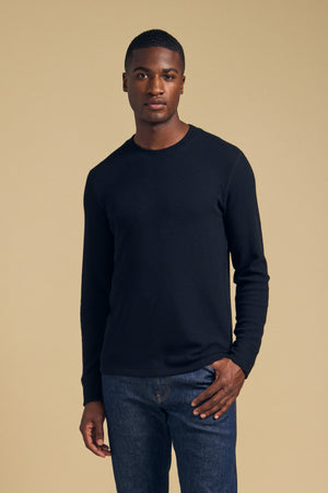 A man wearing a black brushed TOLLIVER THERMAL CREW PULLOVER by Velvet by Graham & Spencer and blue jeans.