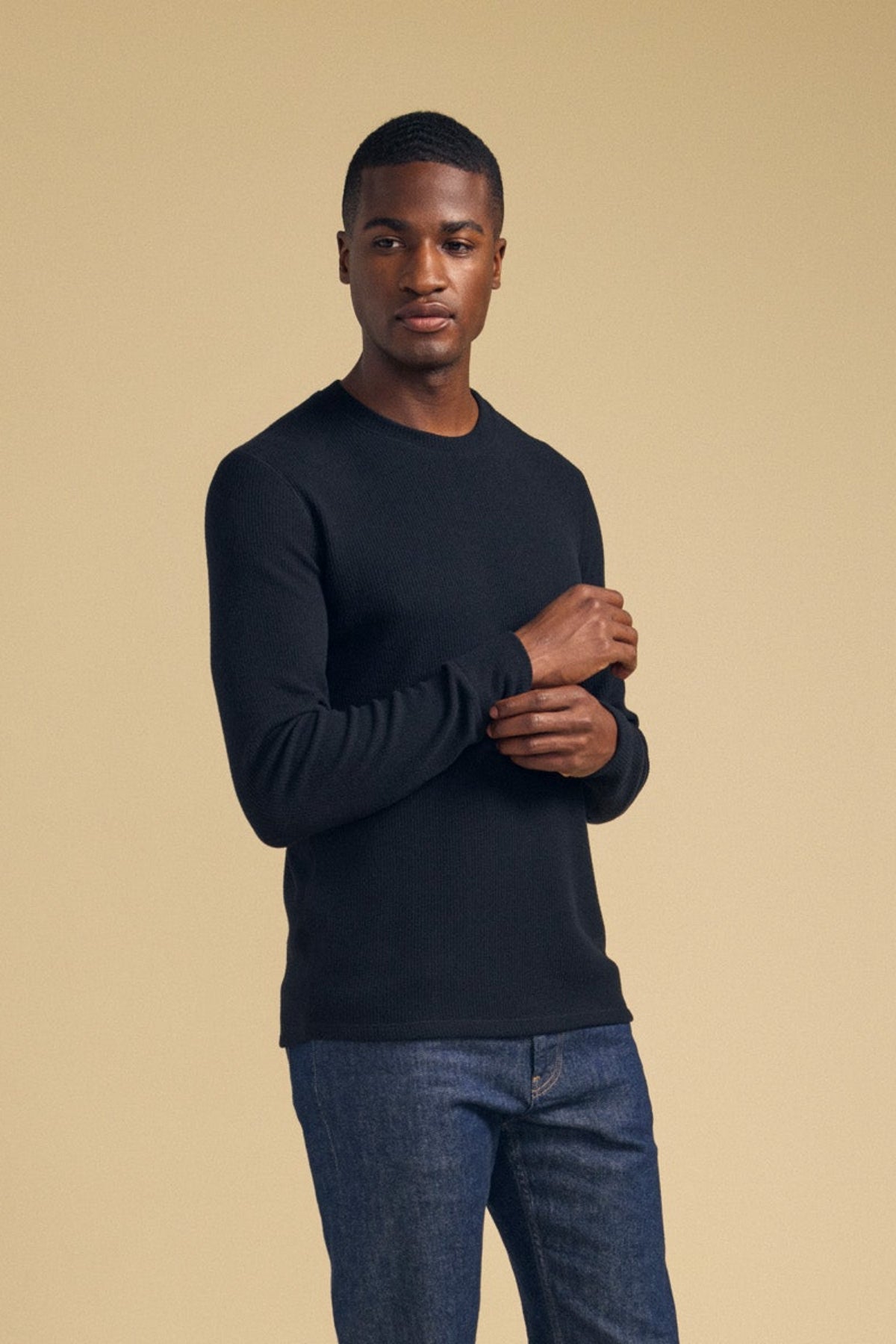 A man wearing a black TOLLIVER THERMAL CREW PULLOVER with a crew neck and blue jeans.-46288499966145