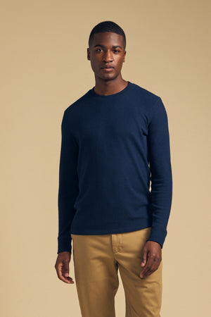 A man wearing a navy blue Velvet by Graham & Spencer TOLLIVER THERMAL CREW PULLOVER and tan trousers.