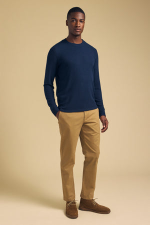 A man wearing a navy blue Velvet by Graham & Spencer TOLLIVER THERMAL CREW PULLOVER, tan chinos, and brown suede chukka boots.