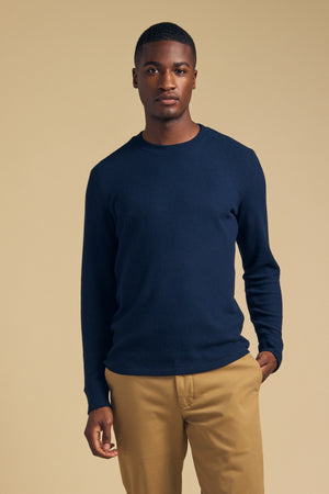 A man wearing a navy blue Velvet by Graham & Spencer TOLLIVER THERMAL CREW PULLOVER and tan trousers.