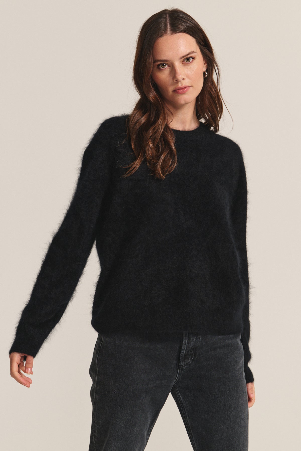 A woman stands against a plain light background, wearing the JACQUELINE CASHMERE SWEATER by Velvet by Graham & Spencer with black jeans, looking directly at the camera.