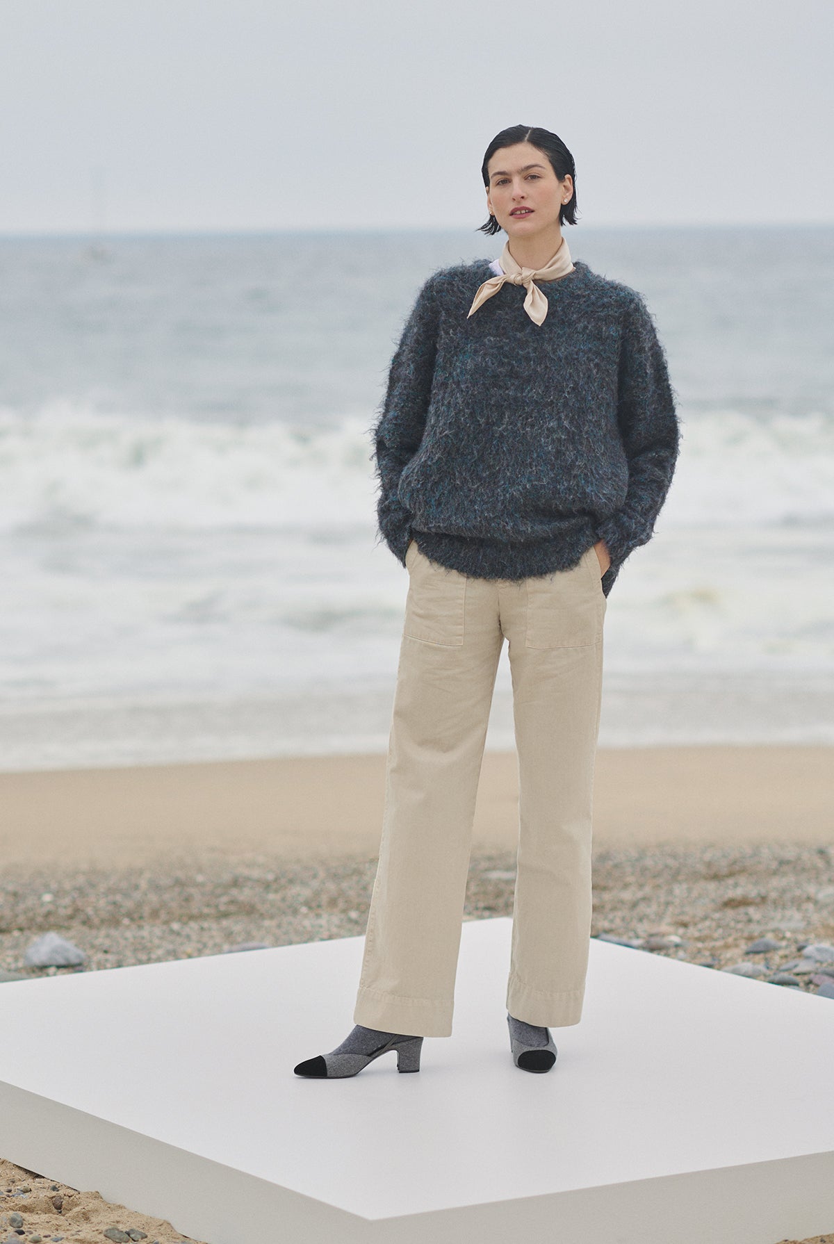 A woman standing on a platform next to the ocean wearing a Velvet by Jenny Graham Valencia sweater and pants that exemplifies wardrobe versatility.-35547899560129