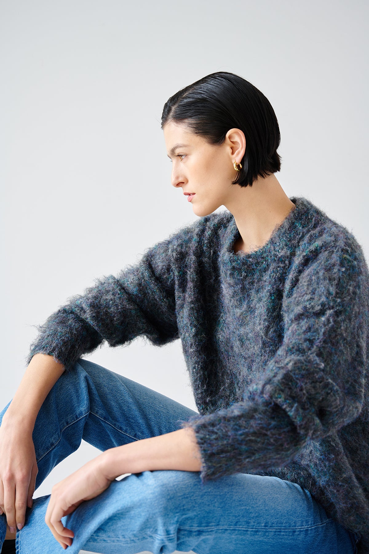A woman wearing a Velvet by Jenny Graham Valencia sweater and jeans sitting on the floor, displaying the versatility of her wardrobe.-35547422752961