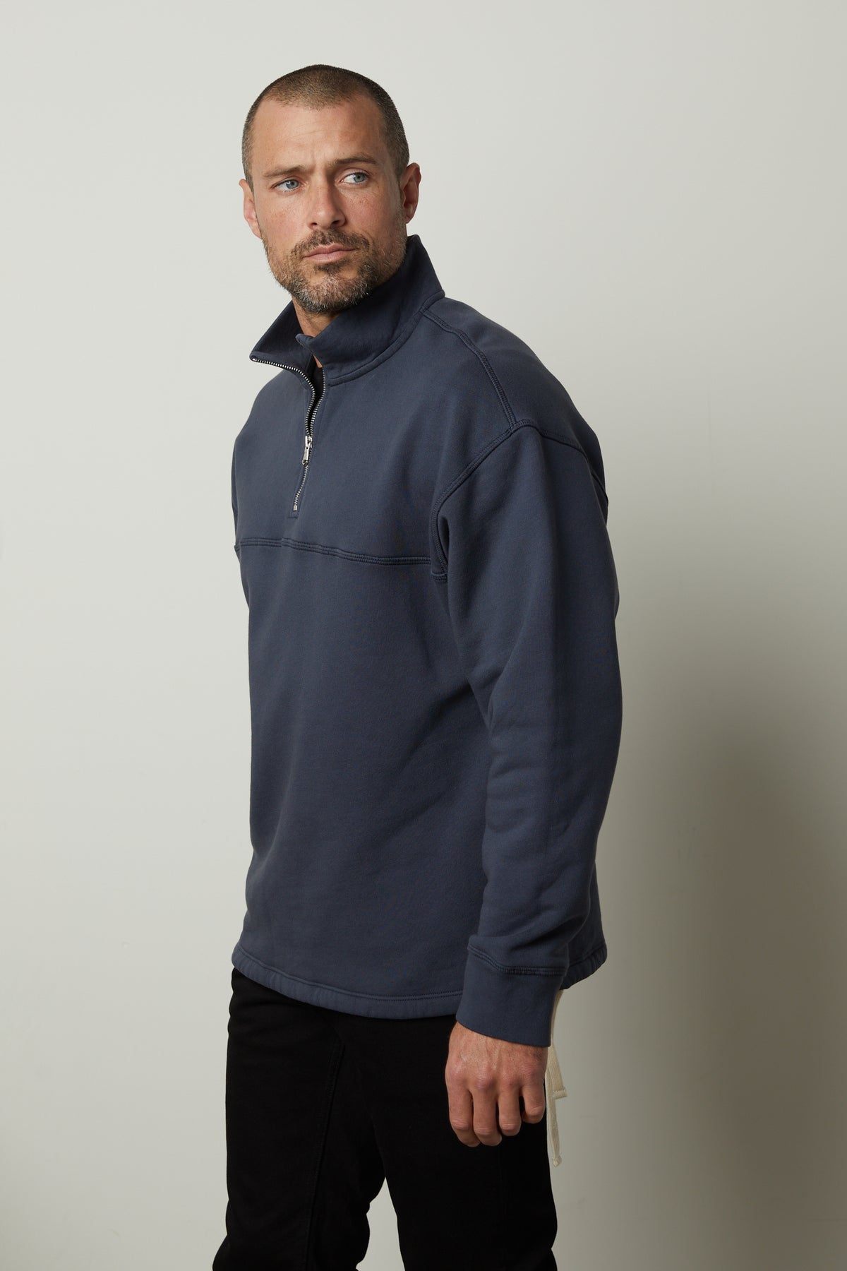 A man wearing a blue Velvet by Graham & Spencer BOSCO quarter-zip sweatshirt and black pants.-35782782648513