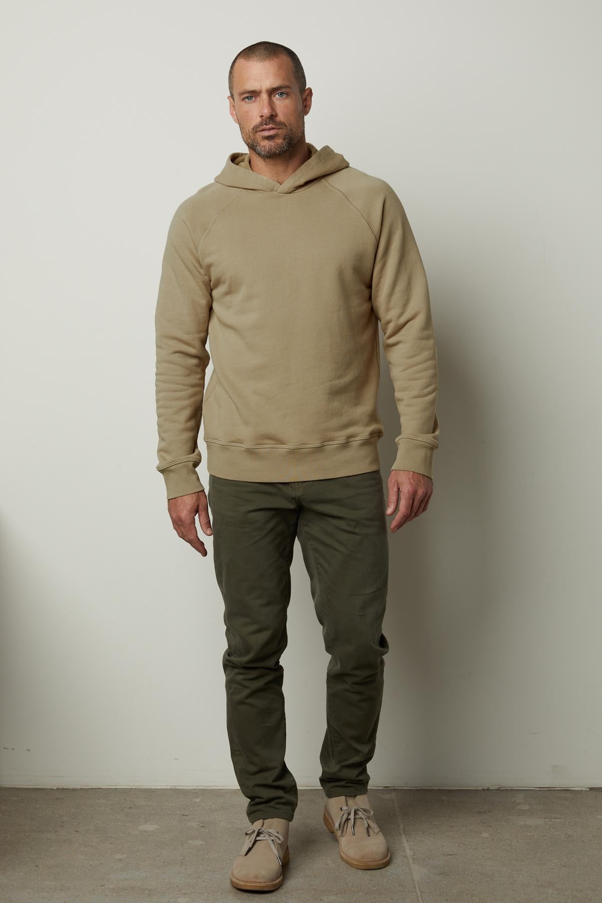 A man wearing a Velvet by Graham & Spencer HOPKIN PULLOVER HOODIE crafted from brushed fleece and khaki pants.-35547533967553