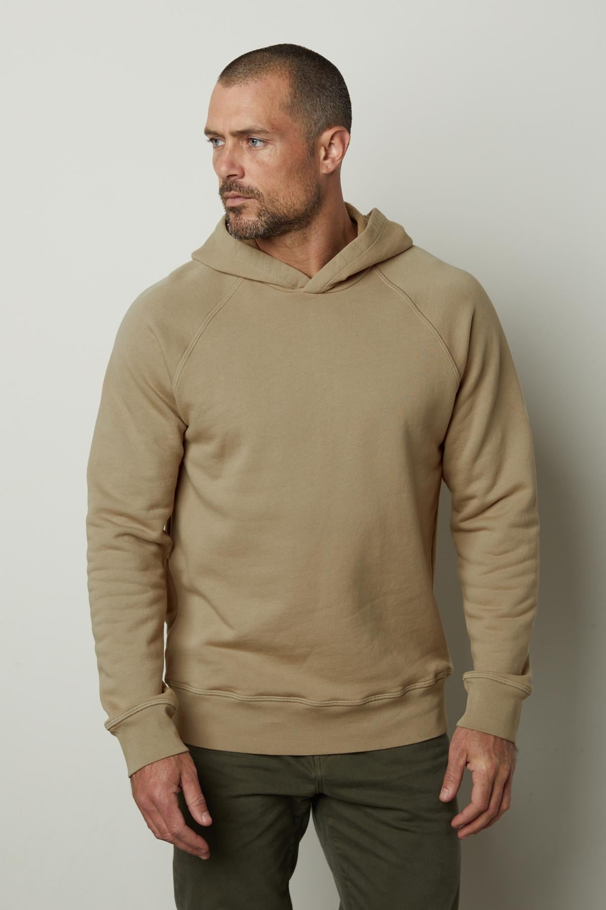   A man wearing a Velvet by Graham & Spencer HOPKIN PULLOVER HOODIE and khaki pants. 