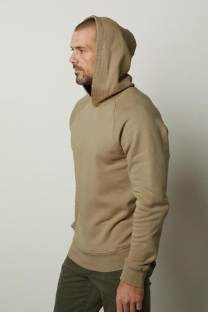 A man wearing a HOPKIN PULLOVER HOODIE crafted for comfort from Velvet by Graham & Spencer.