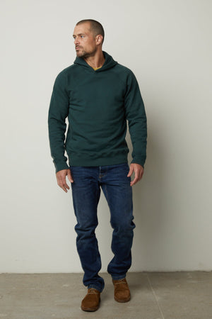 A man enjoying superior comfort in a Velvet by Graham & Spencer HOPKIN PULLOVER HOODIE and jeans made of brushed fleece.