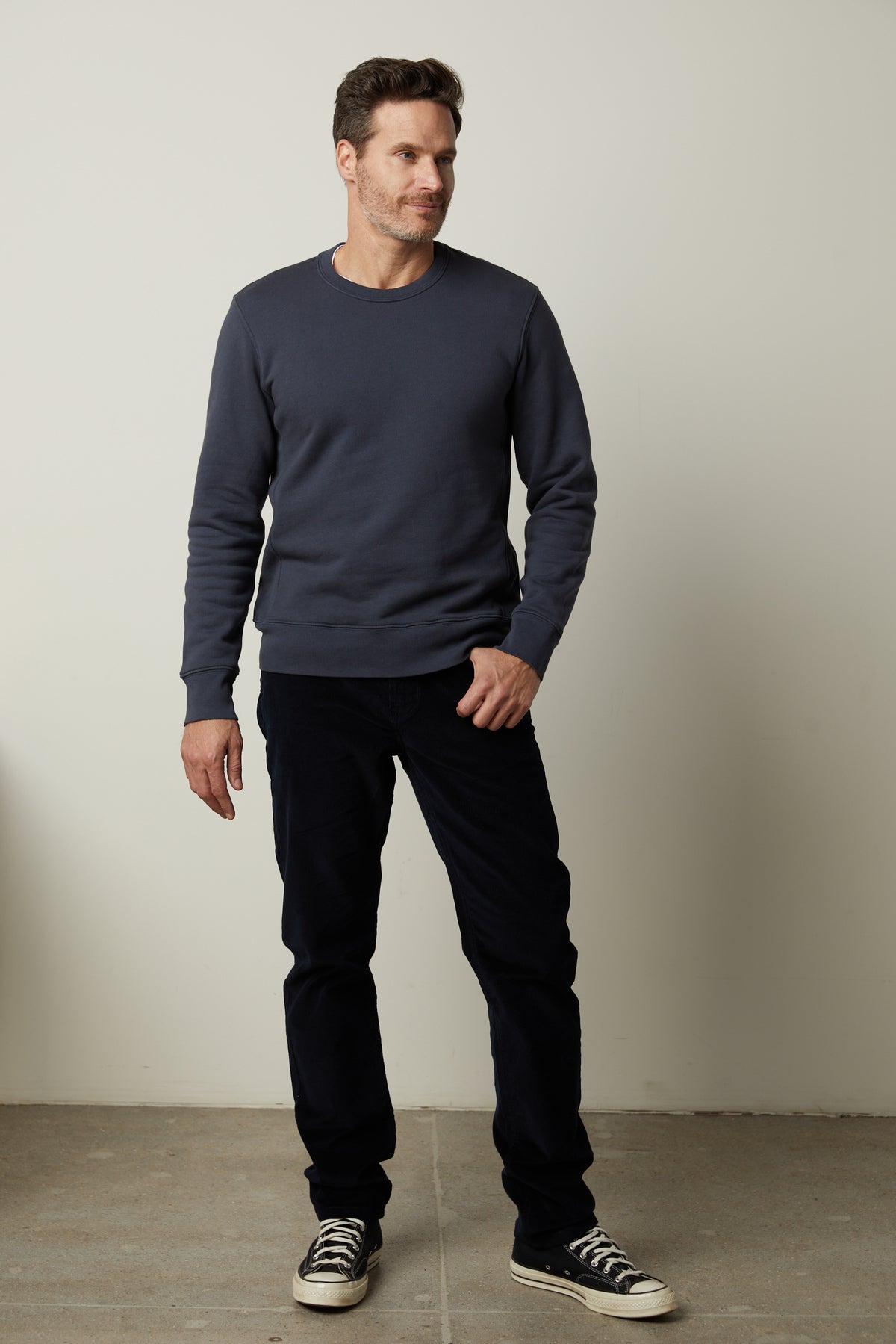   A man standing in a clean room wearing a Velvet by Graham & Spencer KING CREW NECK SWEATSHIRT and pants. 