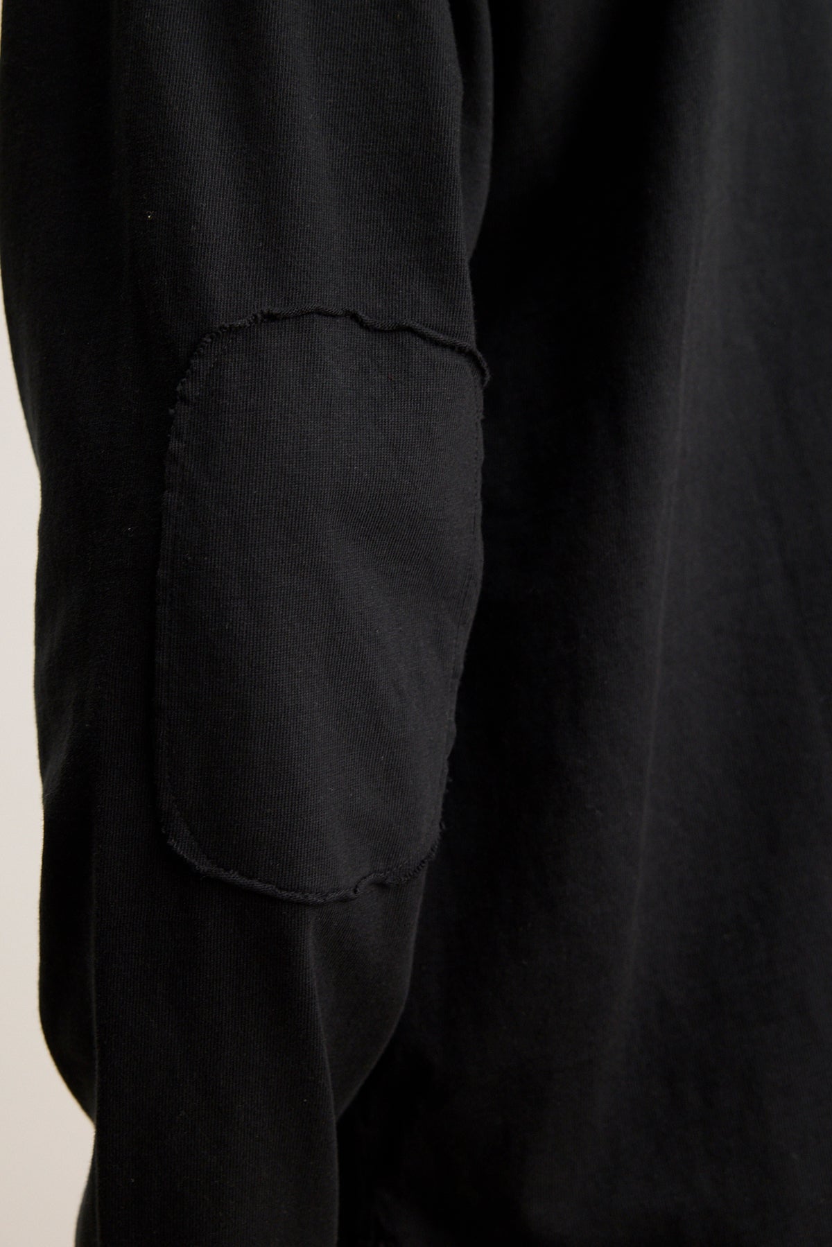   Close-up of a black sleeve from the SLATER TEE by Velvet by Graham & Spencer, crafted from pima cotton jersey with a rectangular elbow patch. This relaxed-fit piece is versatile for any wardrobe. 