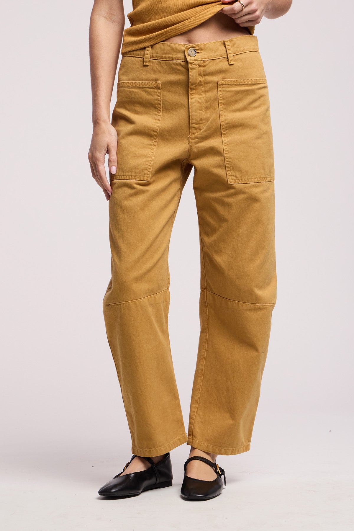 A person wears the BRYLIE PANT by Velvet by Graham & Spencer—tan high-waisted cotton twill trousers with utilitarian patch pockets—paired with black flats, standing against a plain background.-41374540234945
