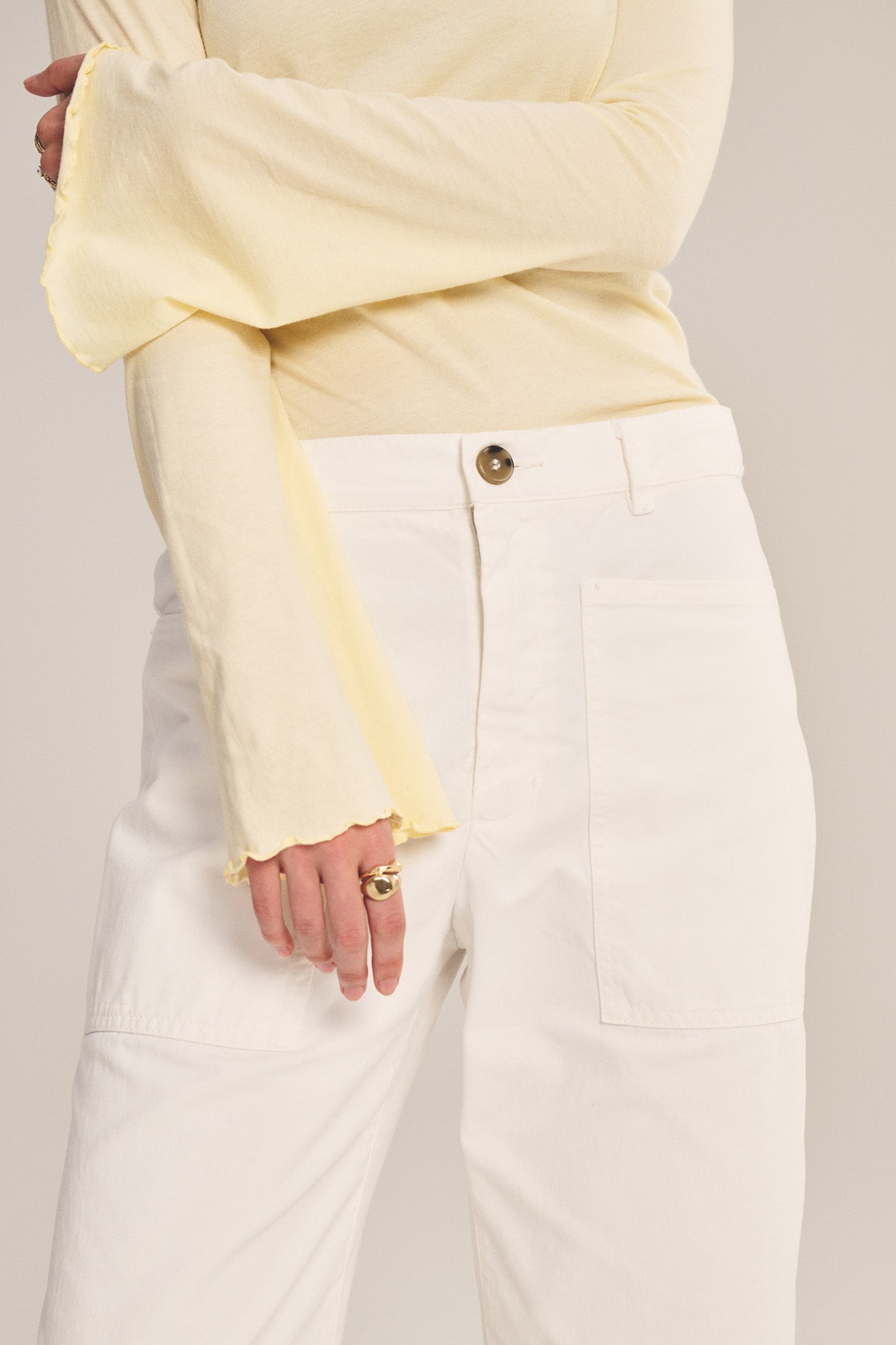 Model wearing Velvet by Graham & Spencer's BRYLIE PANT, a white cotton twill trouser with utilitarian patch pockets, paired with a light yellow long-sleeve top; shown from shoulder to thigh.-40959929221313