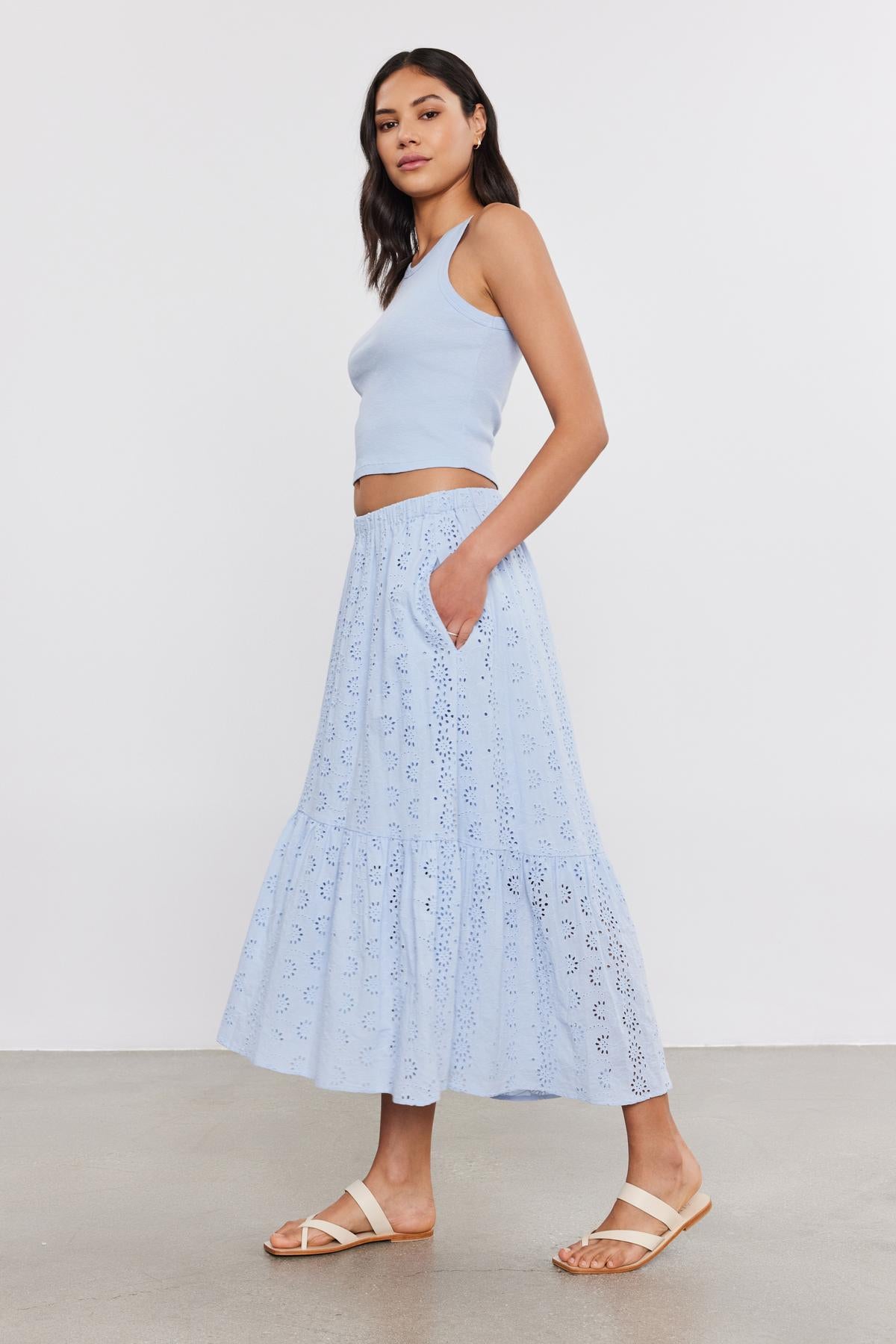 A woman models a Velvet by Graham & Spencer HARLA RIBBED CROPPED TANK TOP and a matching eyelet maxi skirt, standing in a studio with a plain background, paired with light sandals.-36752885907649